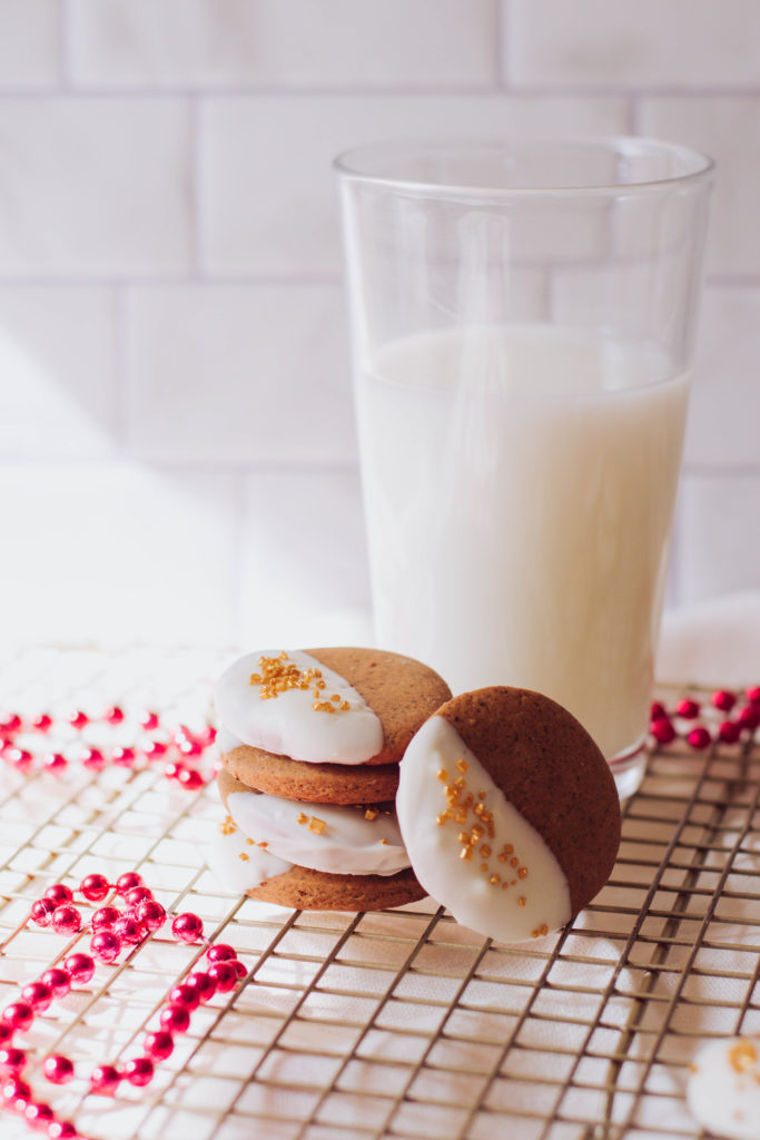 Ginger cookies with half of it dipped in white chocolate and garnished with golden sprinkles.