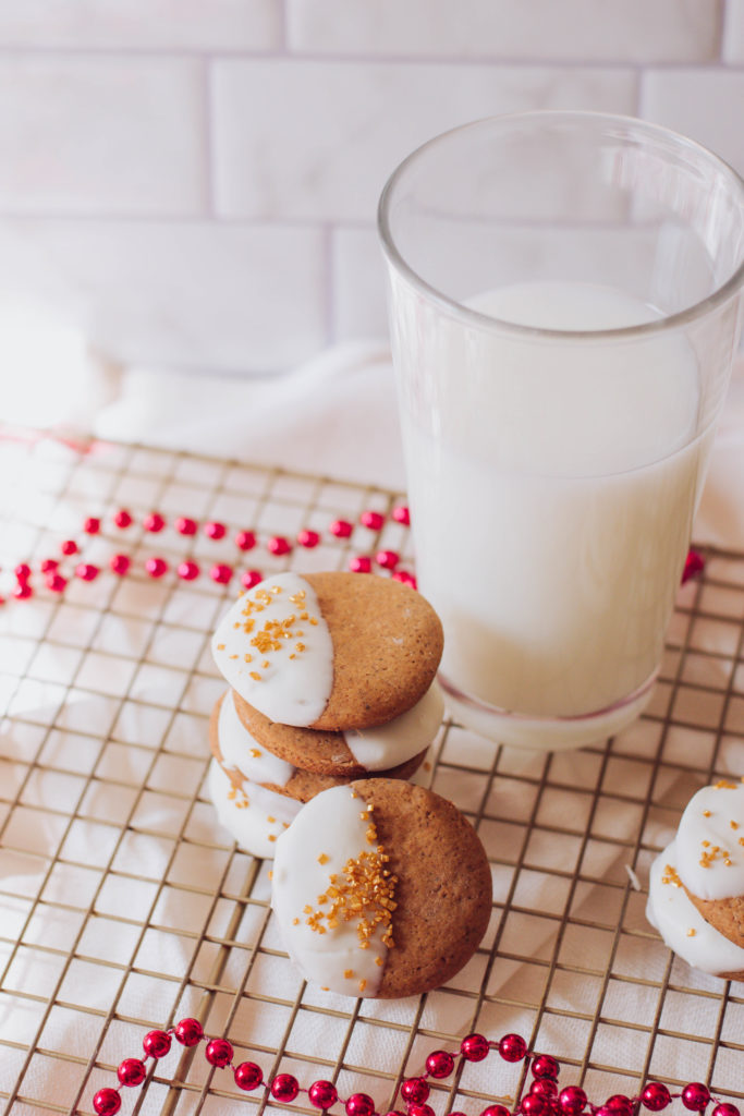 Ginger cookies with half of it dipped in white chocolate and garnished with golden sprinkles.
